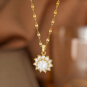 Macro shot of gold sun flower pendant necklace with central gemstone and pavé diamonds