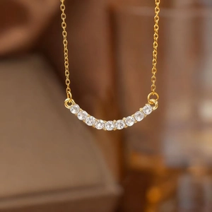 Macro shot of gold necklace with a curved smile pendant set with clear crystals