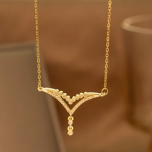 Macro shot of gold V-shaped necklace pendant with shimmering zircon and small round drop