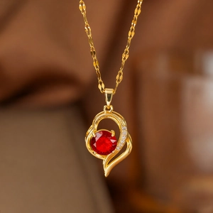 Collana dorata con pendente a cuore asimmetrico, zircone rosso e pietre bianche lucide