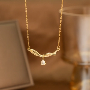 Detailed close-up of golden laurel leaf pendant with pear-shaped zircon and pave crystals