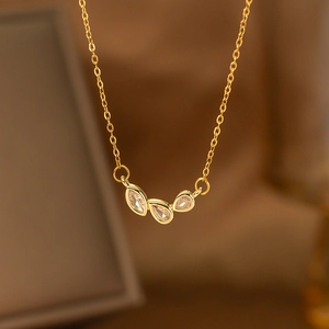 Macro view of gold necklace with three water-drop gemstones and delicate chain