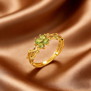 Detailaufnahme des vergoldeten Kleeblattrings mit grünen Herzsteinen auf Seide