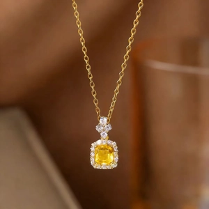Detailed view of square-cut yellow gemstone pendant with diamond halo on gold chain
