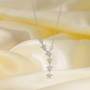 Dettaglio della collana a Y con stelle in argento e zirconi su sfondo di raso