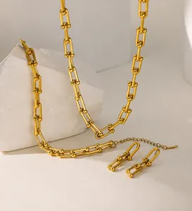 Détail d'un collier à maillons en U dorés avec fermoir mousqueton sur pierre blanche