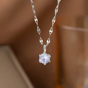 Detailed view of the six-prong solitaire pendant on a reflective silver necklace
