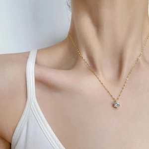 Detailed view of a six-prong round diamond pendant on a delicate gold chain necklace
