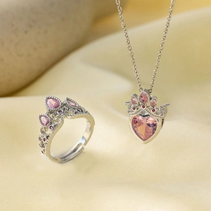 Détail du coffret collier cœur et bague couronne avec zircons roses sur fond satiné