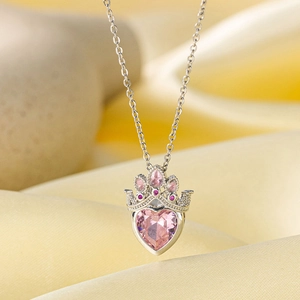 Gros plan d'un pendentif couronne en argent avec pierre coeur rose sur soie