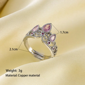 Détail de la bague couronne avec pierres roses et finition argentée sur du satin