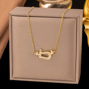Collier fer à cheval doré serti de zircons présenté sur un coffret à bijoux