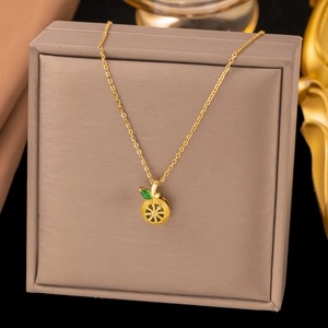 Macro shot of gold lemon slice pendant with green zircon leaves on fine jewelry chain