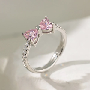 Vue macro d'une bague argentée avec zircons roses en forme de cœur style papillon
