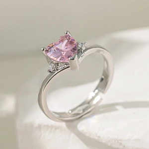 Détail macro d'une bague argentée ajustable avec zircon rose cœur sur support pierre