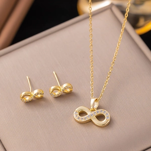 Macro shot of gold infinity jewelry set with cubic zirconia on brown texture