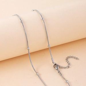 Gros plan d'un collier triple couche en acier inoxydable argenté à perles espacées