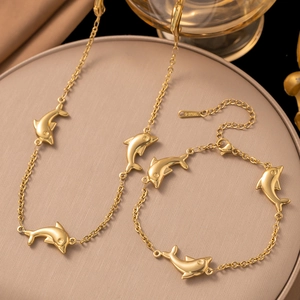 Goldenes Delfin-Halsketten- und Armband-Set aus Edelstahl auf einem Lederständer