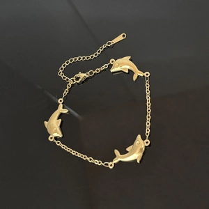 Goldenes Delphin-Anhänger-Armband aus Edelstahl mit verstellbarer Kette auf schwarzem Spiegel