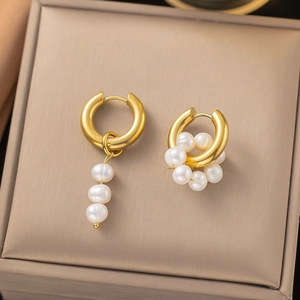 Detail of asymmetric gold hoop earrings with white pearl clusters and vertical drop