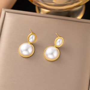 Close-up of golden geometric double ring earrings with embedded white pearls