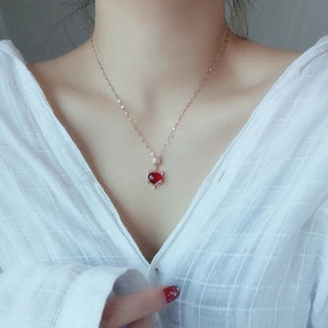 Collar de oro rosa con colgante de corazón rojo en modelo con camisa a cuadros blanca