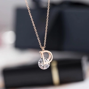 Detalle del colgante letra D en oro rosa con circón brillante en una fina cadena cruzada