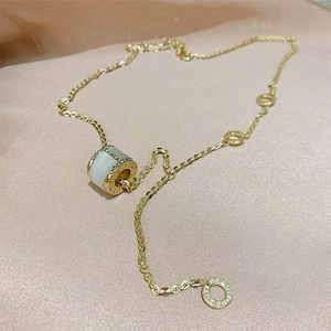 Détail du pendentif cylindre doré avec pierre œil de chat et cristaux sur de la soie