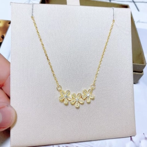 Detailed view of gold clover necklace with three sparkling flower pendants on a chain