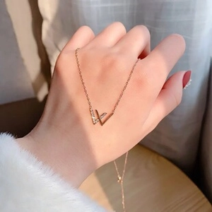 Detail of rose gold V-shaped pendant necklace with cubic zirconia worn on hand