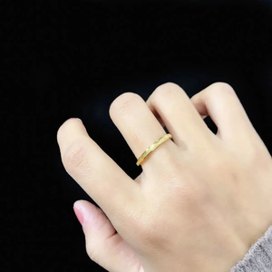 Close-up of minimalist gold titanium ring with a frosted sand finish texture on finger