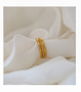 Detail of three-layer gold-plated rings with contrasting polished and frosted textures