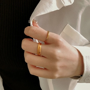 Close-up of stacked gold titanium rings with matte and polished finishes on model hand