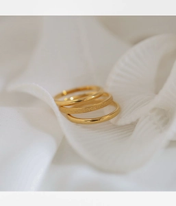 Three-piece stackable gold rings set with matte and polished finishes on white fabric