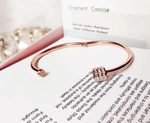 Dettaglio di un bracciale in oro rosa con cilindro con cristalli e chiusura a cerniera