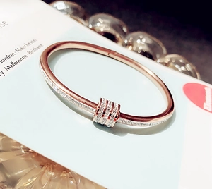 Macro di un bracciale rigido in oro rosa con perla portafortuna e zirconi incastonati