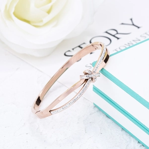 Dettaglio di un bracciale a nodo in oro rosa con micro-pave di zirconi e sfondo floreale