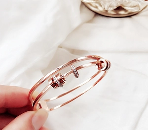 Dettaglio di bracciale rigido a doppio strato in oro rosa con charm in zirconi