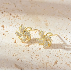 Close-up of golden windmill stud earrings with sparkling pave-set cubic zirconia stones