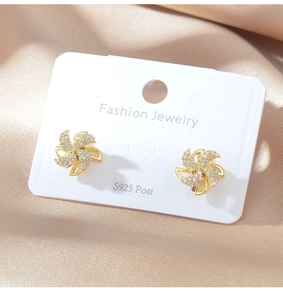 Detailed close-up of golden windmill stud earrings with S925 silver posts and white zircons