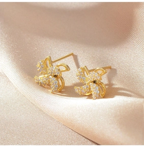 Macro view of gold-plated windmill stud earrings featuring micro-set sparkling zircons