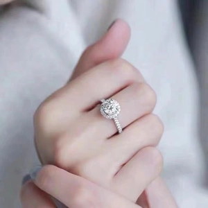 Prachtige 1 karaat moissanite ring met halo-zetting op de hand van een vrouw