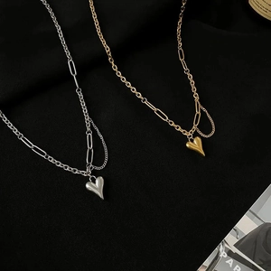 Detail van grove hartvormige hanger kettingen in goud en zilver op zwarte stof