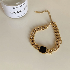 Detail of gold Cuban link bracelet with a black square charm and adjustable clasp