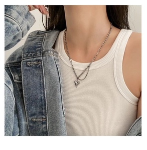 Zilveren hart hanger ketting met grove schakels gedragen door model in een spijkerjasje