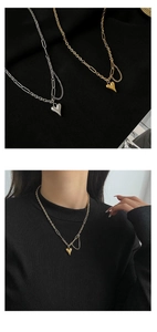 Detail van hart hanger ketting met dikke schakels en kwastje op zwarte stof en bij model