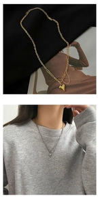 Detail van gouden hartvormige hanger ketting met asymmetrische gelaagde schakels