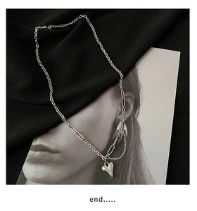 Macro-opname van zilveren hartjes hanger met grove ketting op zwart fluwelen achtergrond