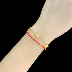 Close-up of double-layer bracelet with red woven rope, gold chain and star charms