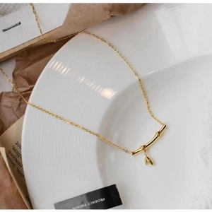 Elegant gold bamboo pendant necklace with small leaf charms on a minimalist O-chain